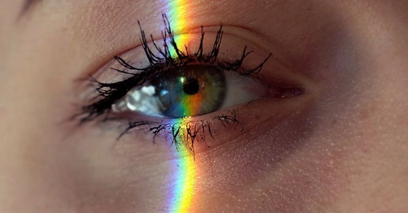 Creative Minds - Closeup of crop anonymous sad female with green eyes and rainbow light on face looking at camera