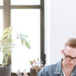 Remote Work - Man in Blue Denim Jacket Sitting by the Table