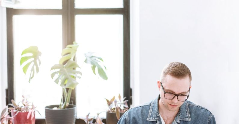 Remote Work - Man in Blue Denim Jacket Sitting by the Table