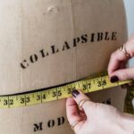 Flexible Work - Crop unrecognizable female dressmaker with flexible ruler measuring hip line of dummy while working in studio